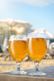 Cold beer in glass on beach. Space for text