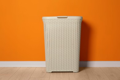 Empty laundry basket near orange wall indoors