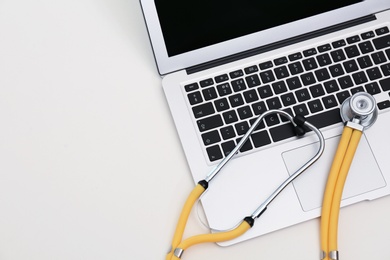 Photo of Modern laptop and stethoscope on table, space for text. Technical support concept