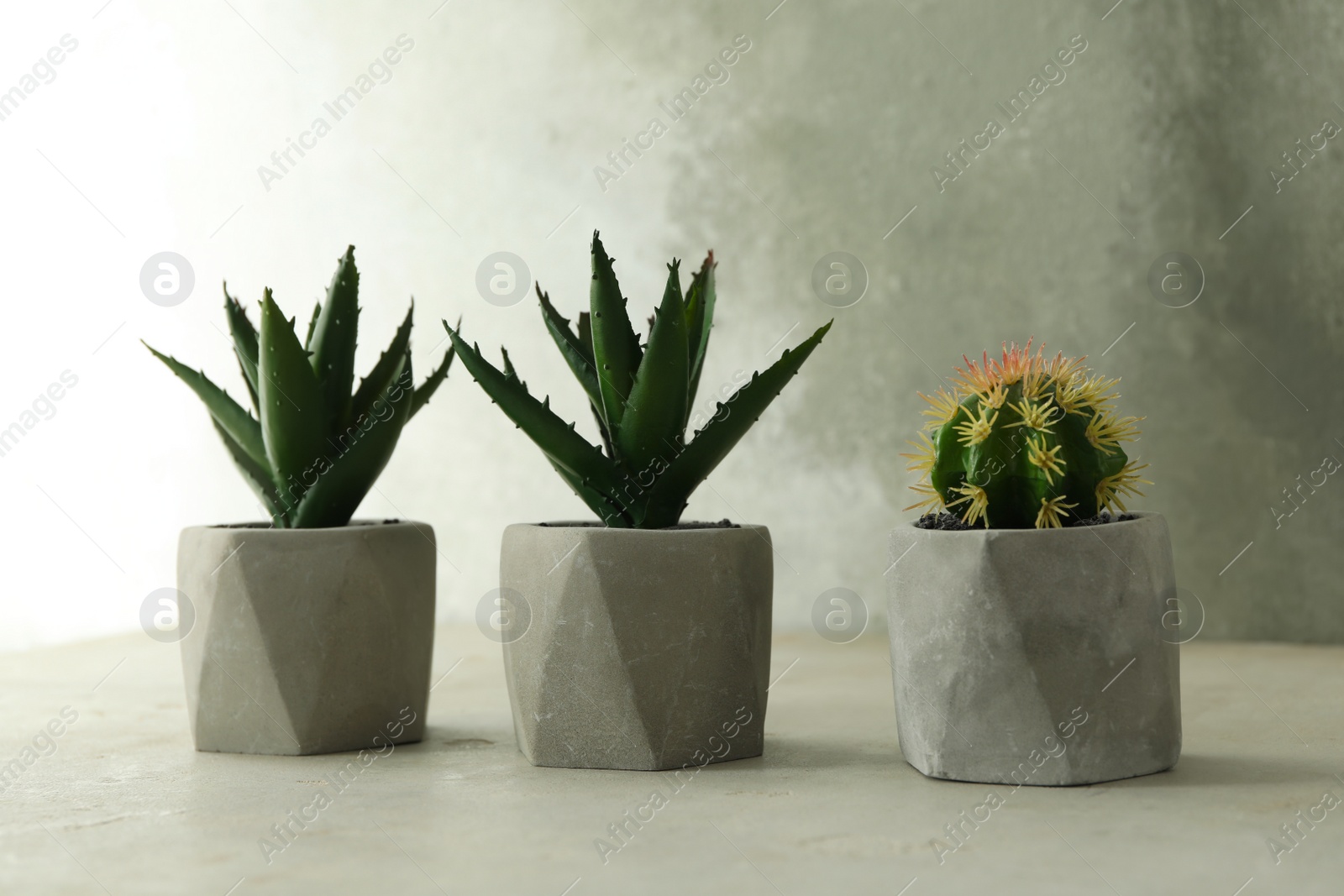 Photo of Artificial plants in flower pots on light grey stone table