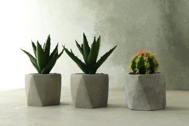 Artificial plants in flower pots on light grey stone table