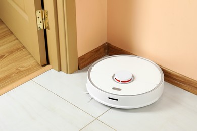 Photo of Modern robotic vacuum cleaner on white floor indoors