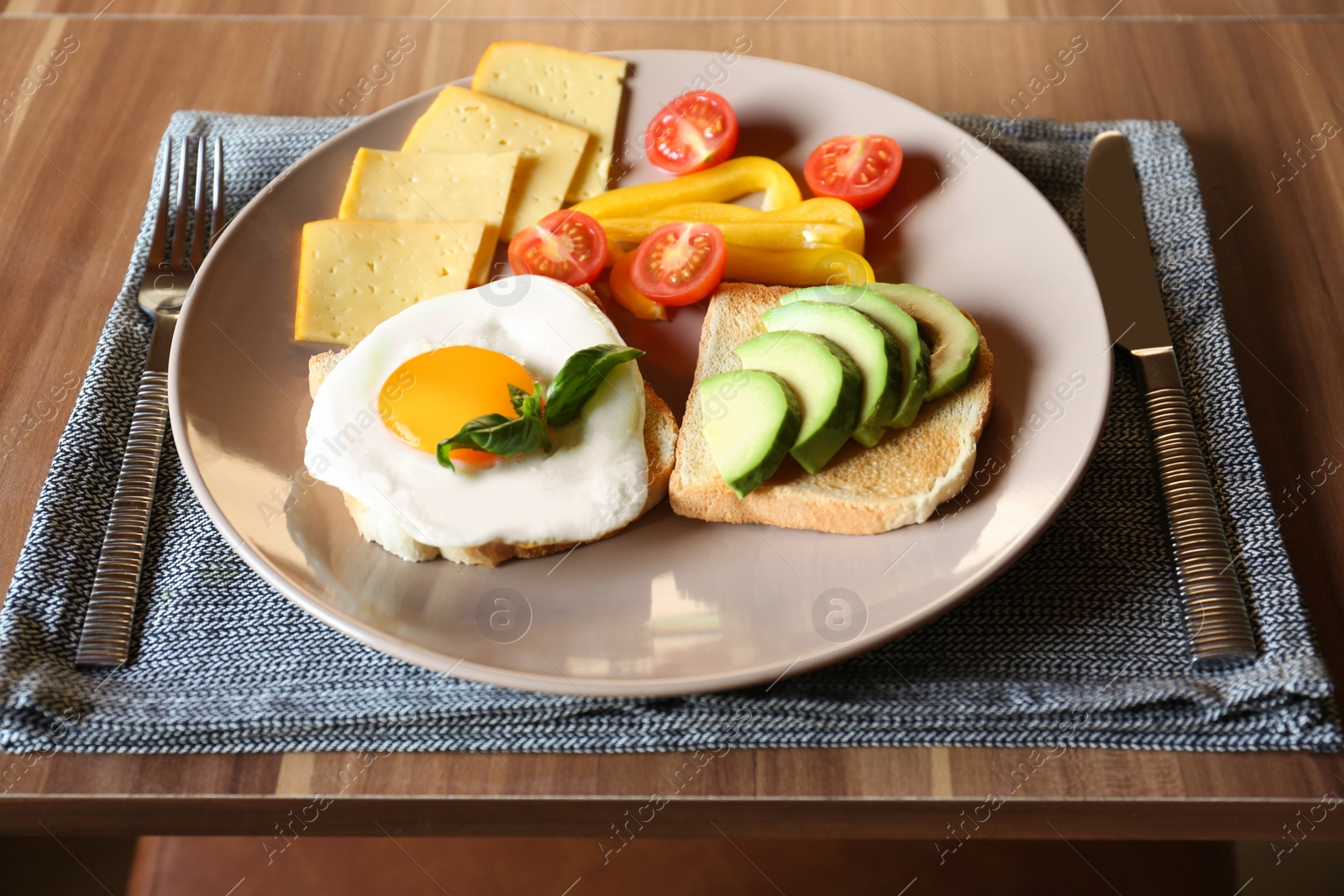 Photo of Tasty toasts with fried egg, avocado, cheese and vegetables served on wooden table