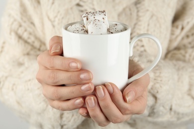 Photo of Woman in sweater holding cup of delicious marshmallow cocoa, closeup