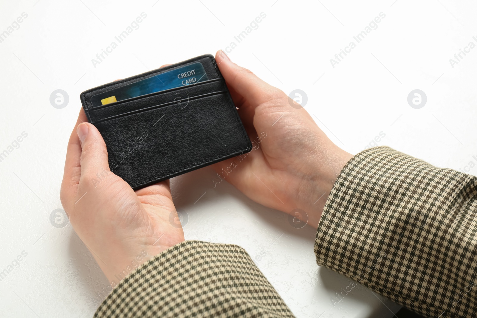 Photo of Woman holding leather card holder with credit card at white table, closeup