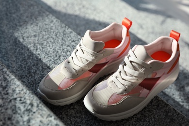 Photo of Pair of stylish women's sneakers on grey marble stairs indoors