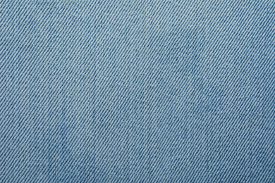 Photo of Texture of light blue jeans as background, closeup