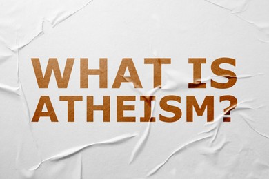 Phrase What Is Atheism? on white creased paper
