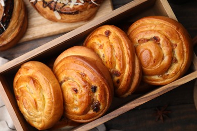 Photo of Different delicious rolls on wooden table, flat lay. Sweet buns