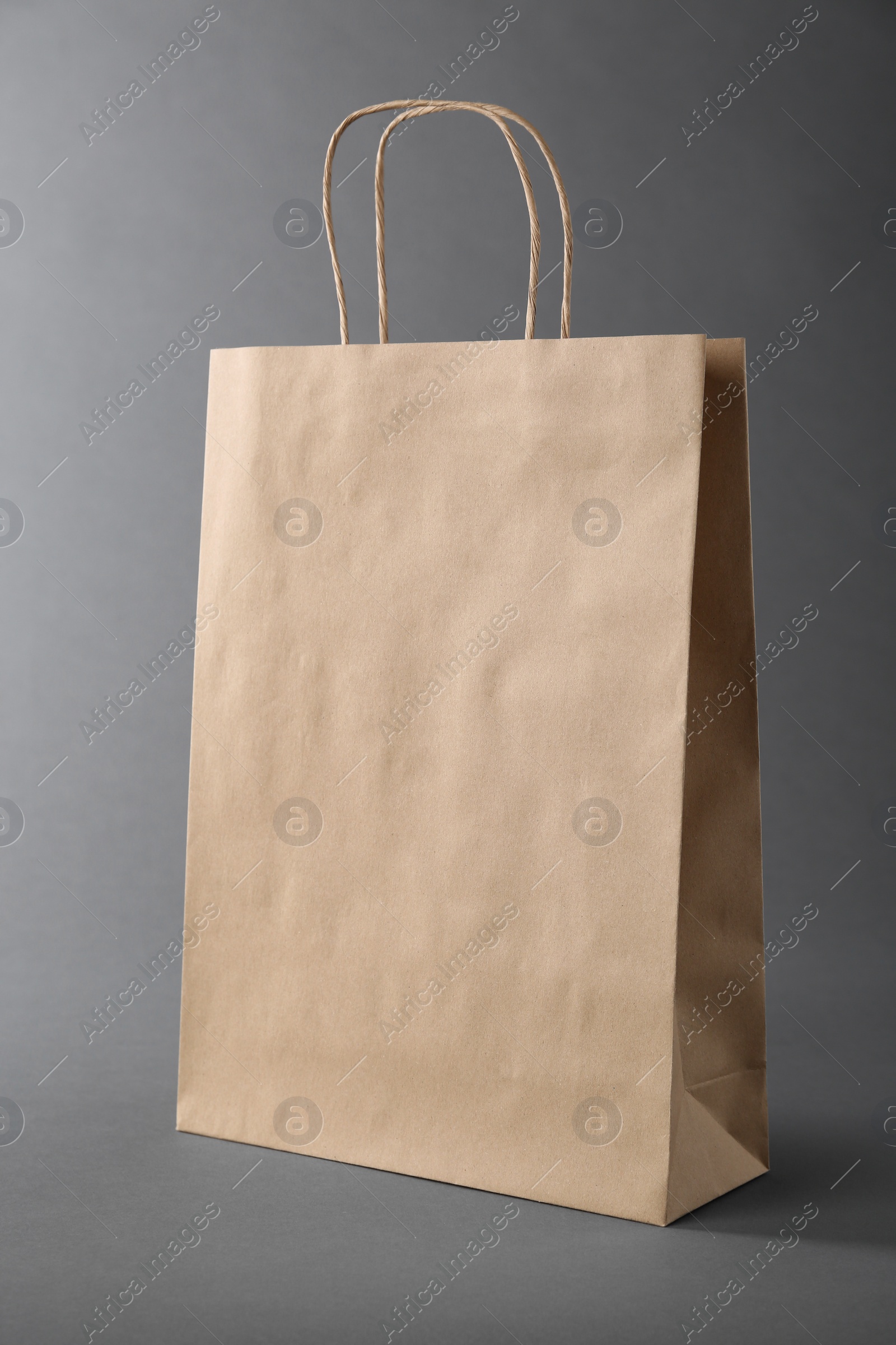 Photo of One kraft paper bag on grey background. Mockup for design