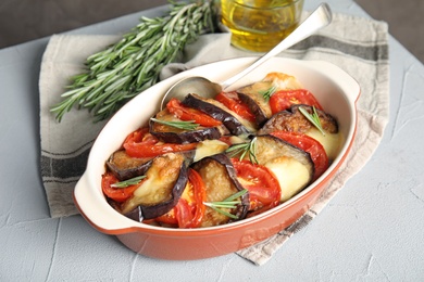 Baked eggplant with tomatoes, cheese and rosemary in dishware on table