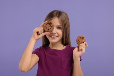 Cute girl with chocolate chip cookies on purple background