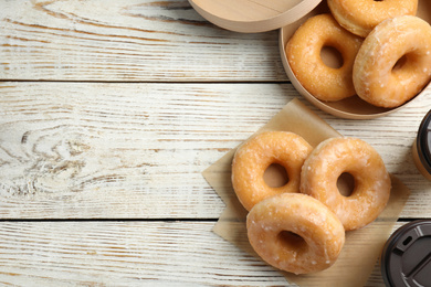 Photo of Delicious donuts on white wooden table, flat lay. Space for text