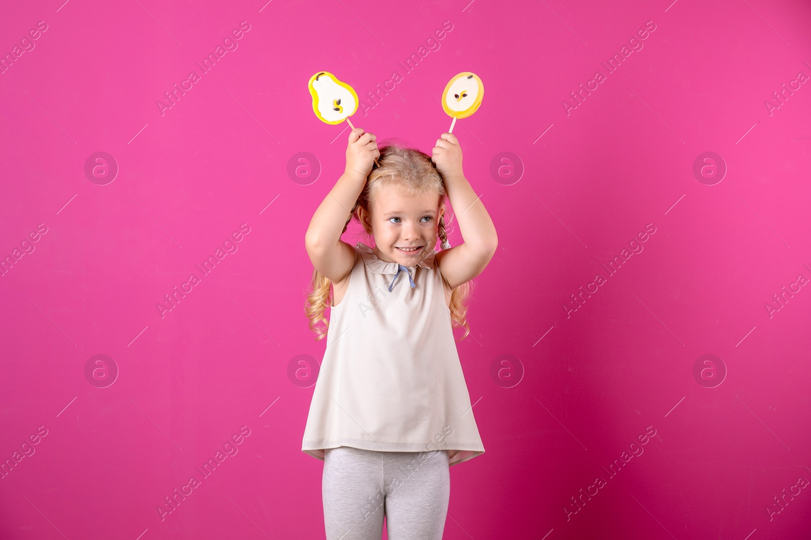 Photo of Cute little girl with candies on color background