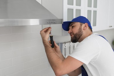 Photo of Worker repairing modern cooker hood in kitchen