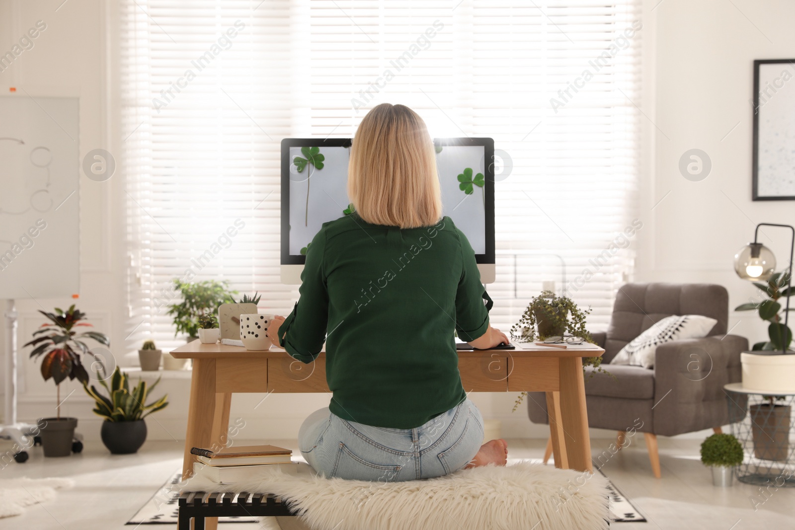 Photo of Woman working at table in light room, back view. Home office