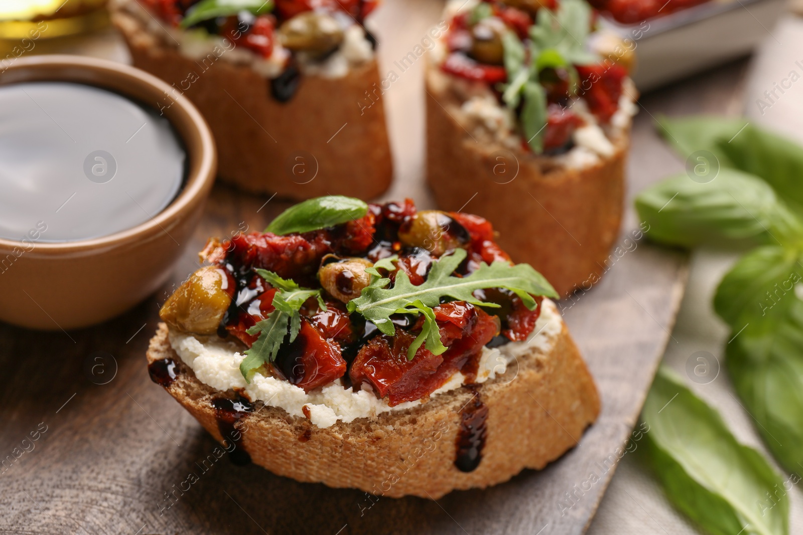 Photo of Delicious bruschettas with balsamic vinegar and toppings on table, closeup