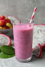 Photo of Glass of tasty pitahaya smoothie and fresh fruits on light grey table