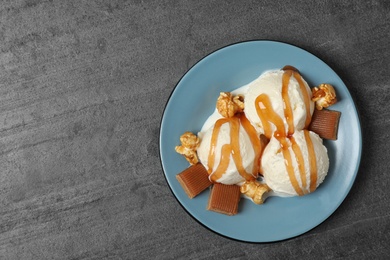 Delicious ice cream with caramel topping on grey table, top view. Space for text