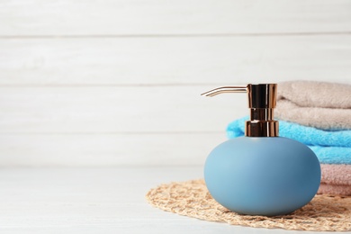 Photo of New stylish soap dispenser and towels on table. Space for text