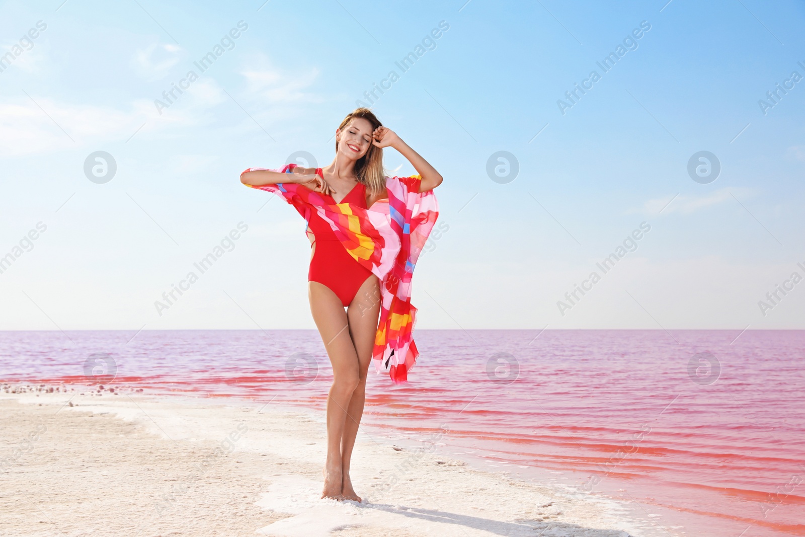 Photo of Beautiful woman in swimsuit posing near pink lake on sunny day