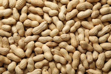 Photo of Many fresh unpeeled peanuts as background, top view