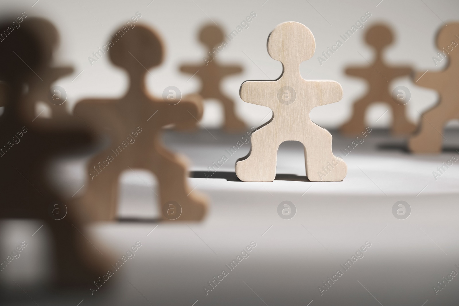 Photo of Recruitment and hiring concept. Human wooden figure in beam of light among others on table