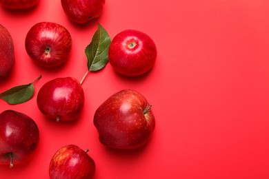 Photo of Ripe red apples and green leaves on color background, flat lay. Space for text