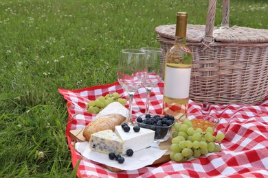 Picnic blanket with delicious food and wine outdoors on summer day