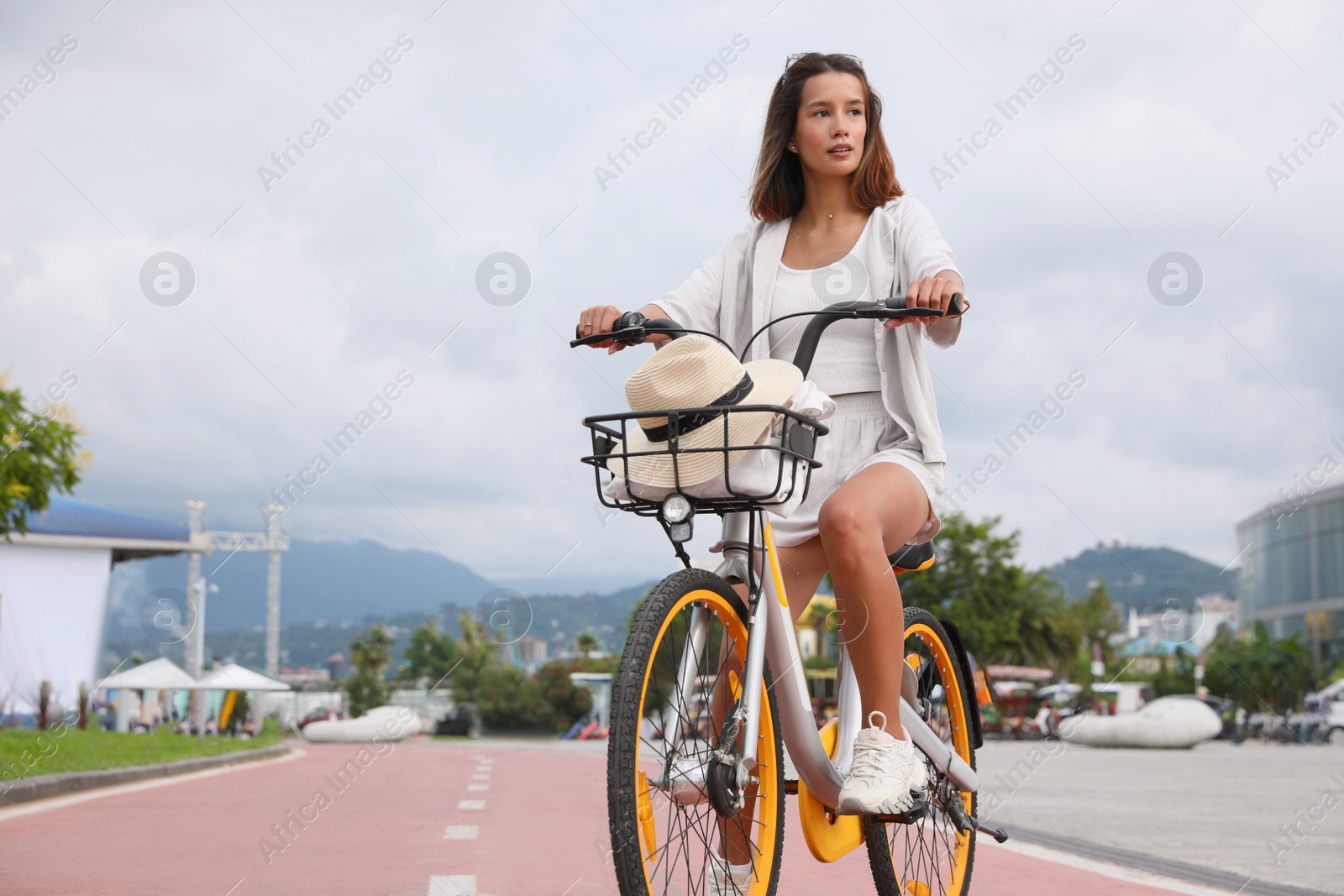 Photo of Beautiful young woman riding bicycle on lane in city. Space for text