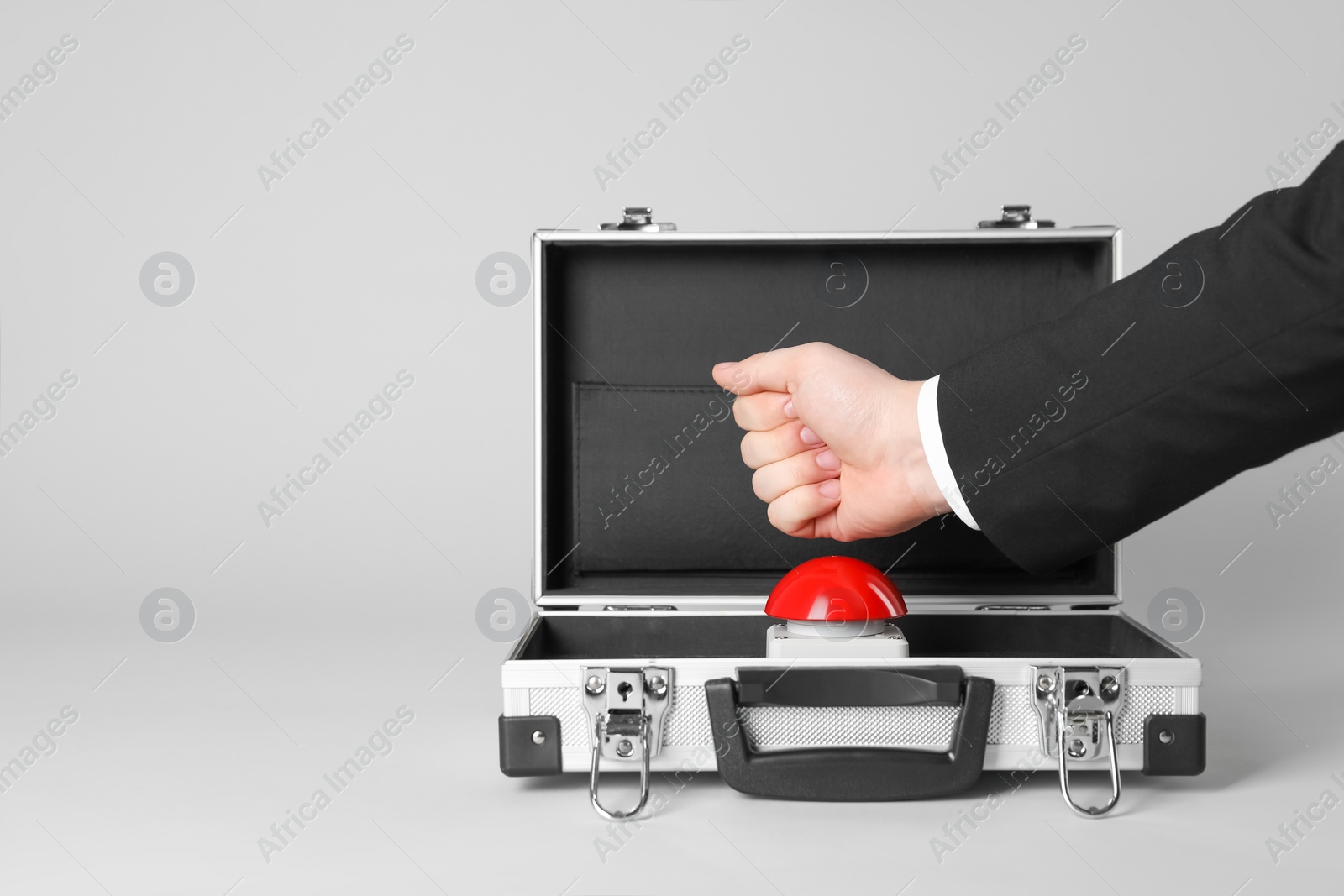 Photo of Man pressing red button of nuclear weapon on light gray background, closeup with space for text. War concept