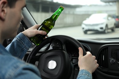 Photo of Man with bottle of beer driving car, closeup. Don't drink and drive concept