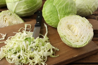 Photo of Chopped ripe cabbage and knife on wooden board, closeup