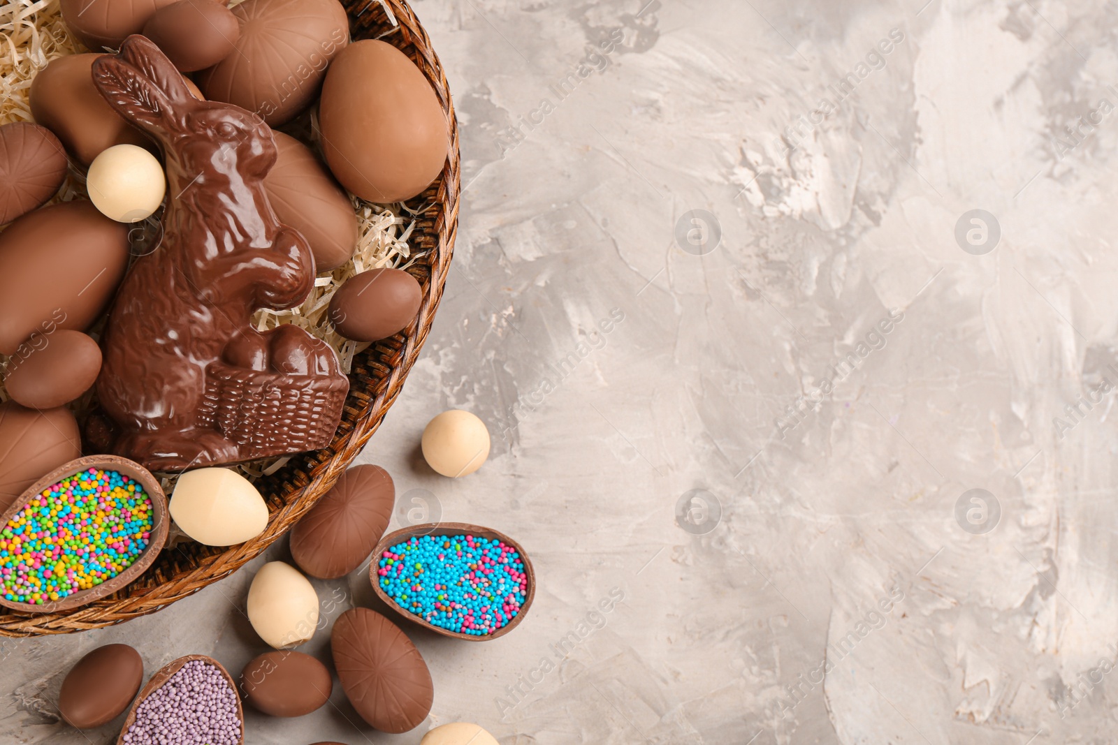 Photo of Flat lay composition with chocolate Easter bunny and eggs on light grey table. Space for text