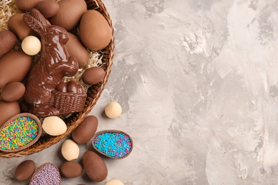 Photo of Flat lay composition with chocolate Easter bunny and eggs on light grey table. Space for text