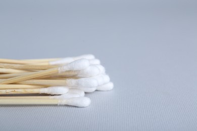 Photo of Wooden cotton buds on light grey background, closeup. Space for text