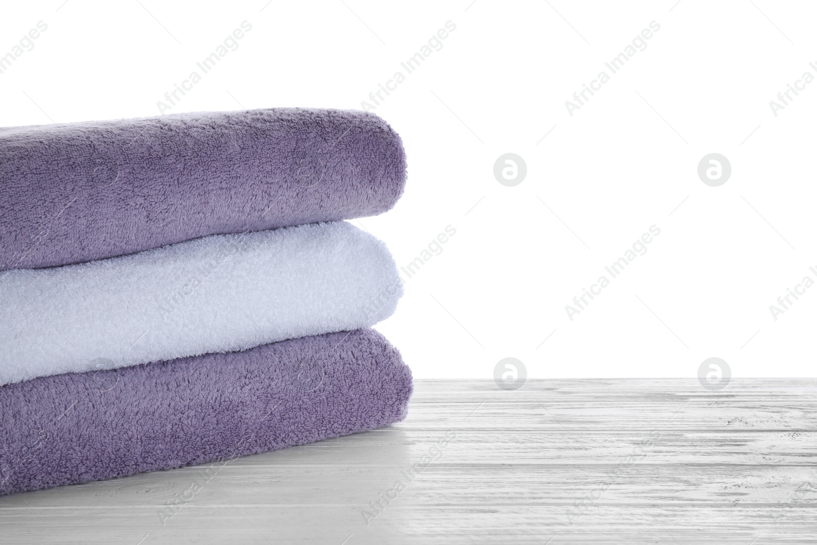 Photo of Fresh towels on wooden table against white background. Space for text