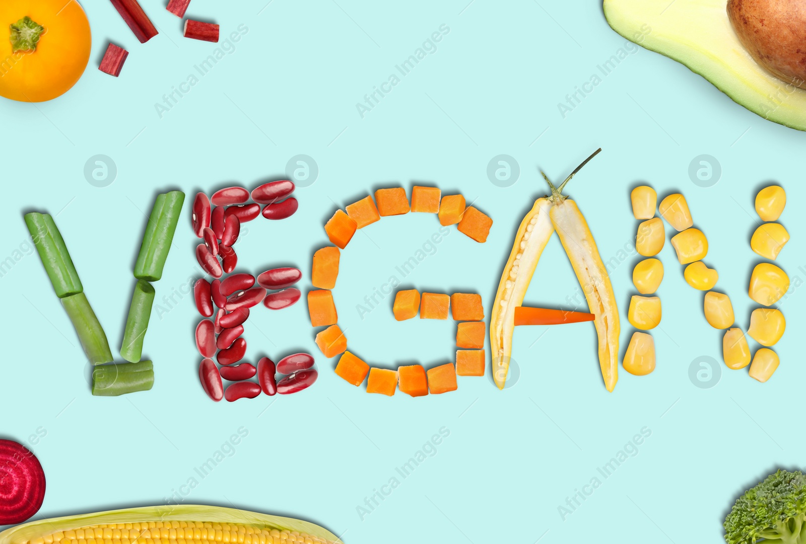 Image of Word VEGAN made of different fresh tasty vegetables on light blue background, flat lay