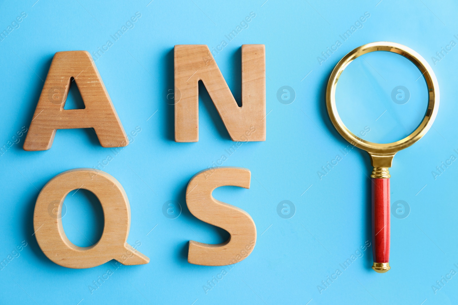 Photo of Wooden letters and magnifier glass on light blue background, flat lay. Find keywords concept