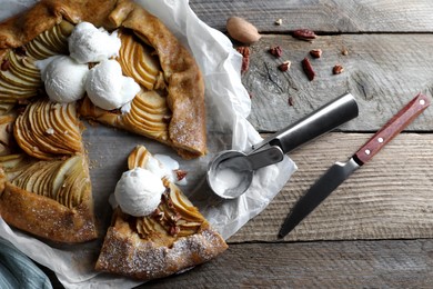 Photo of Delicious apple galette served with ice cream on wooden table, flat lay