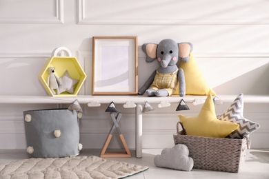 Empty photo frame and cute toys near wall in baby room. Interior design