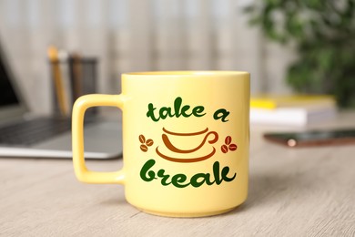 Image of Cup of coffee with inscription Take a Break on wooden table in office