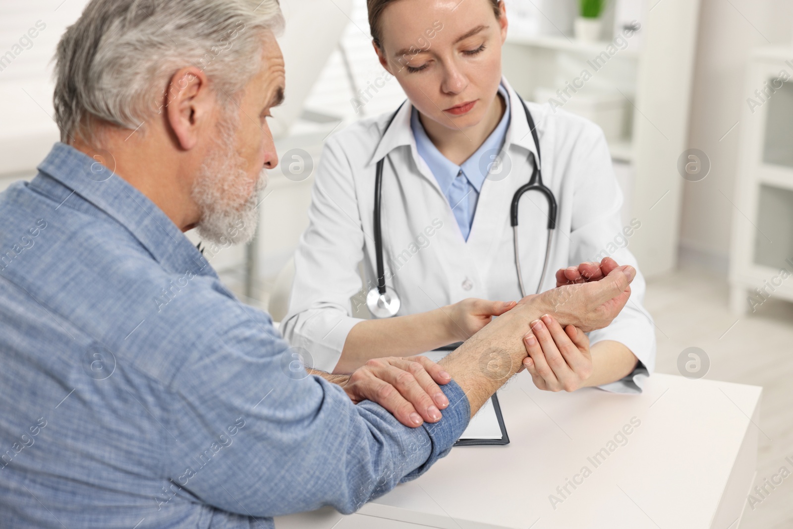 Photo of Arthritis symptoms. Doctor examining patient's wrist in hospital