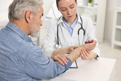 Arthritis symptoms. Doctor examining patient's wrist in hospital