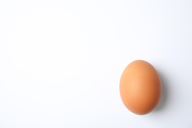 Photo of Raw brown chicken egg on white background, top view