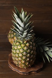 Photo of Two whole ripe pineapples on wooden table