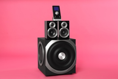 Photo of Modern powerful audio speaker system with remote on pink background