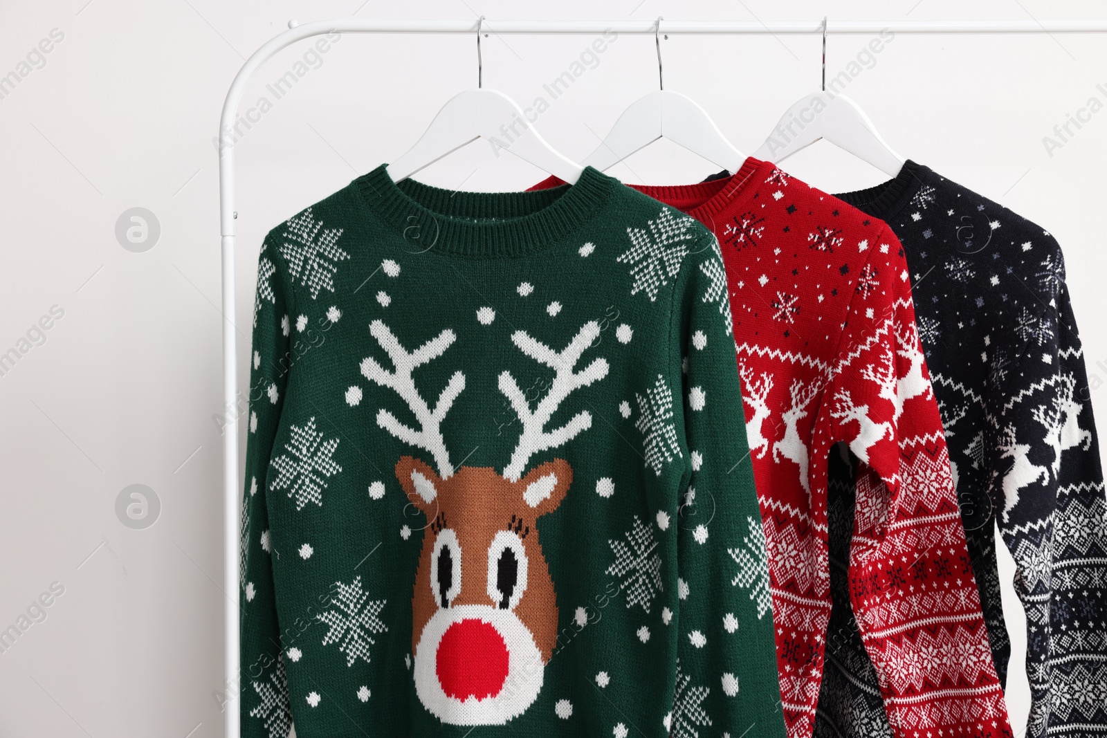 Photo of Rack with different Christmas sweaters on white background