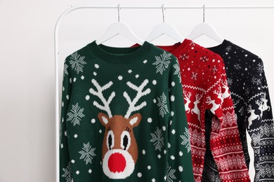 Rack with different Christmas sweaters on white background