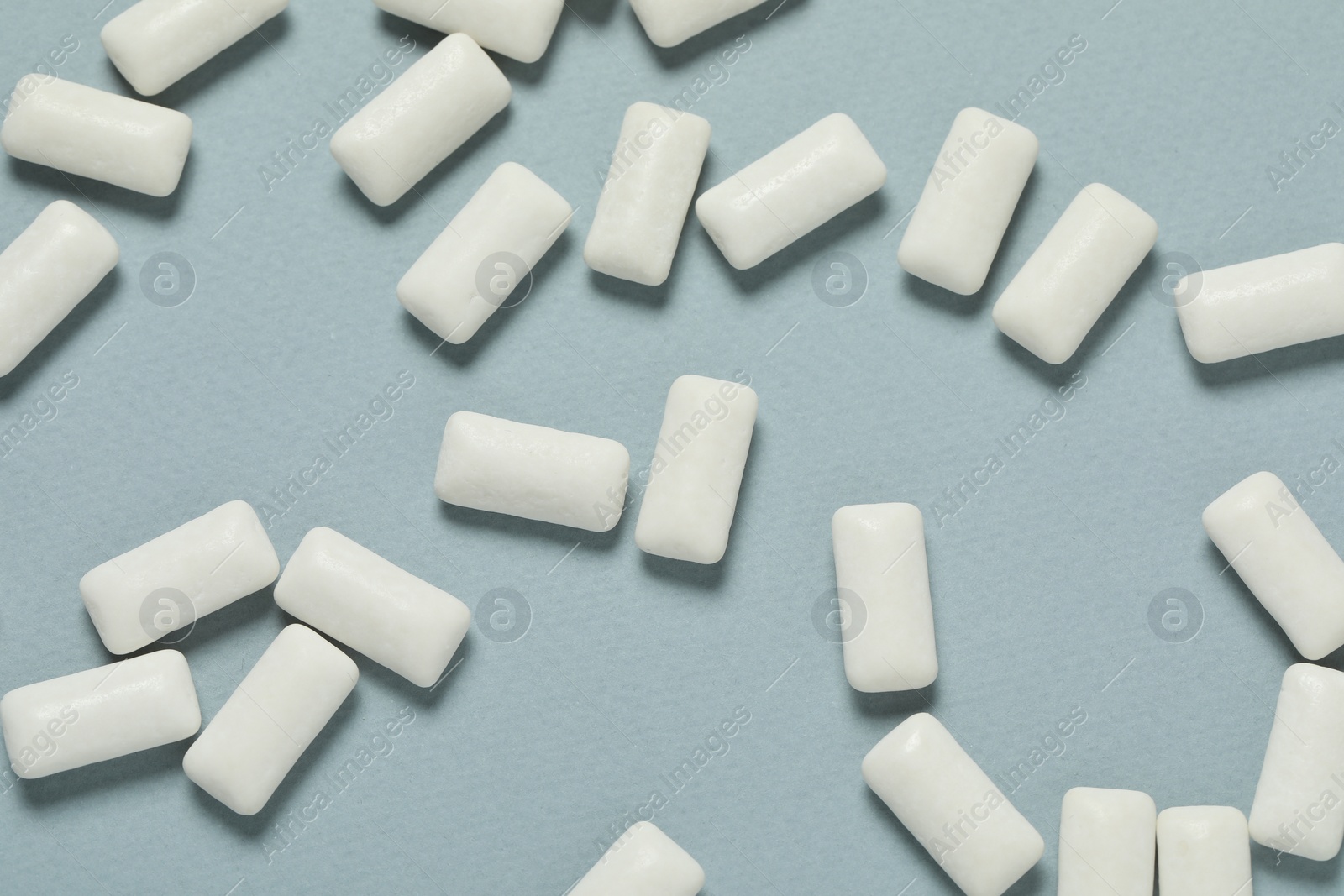 Photo of Tasty white chewing gums on light blue background, flat lay